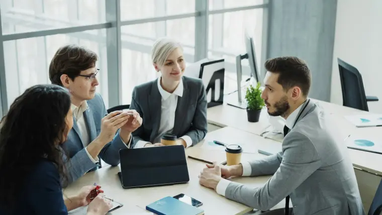 Quatre collègues d'un cabinet réunis autour d'une même table, chacun avec ses documents.