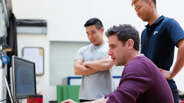 Trois personnes d'une équipe technique vérifient ensemble une fiche à l'écran.